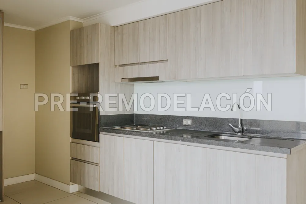 Cocina con horno empotrado y cubierta gris, departamento Portugal 990