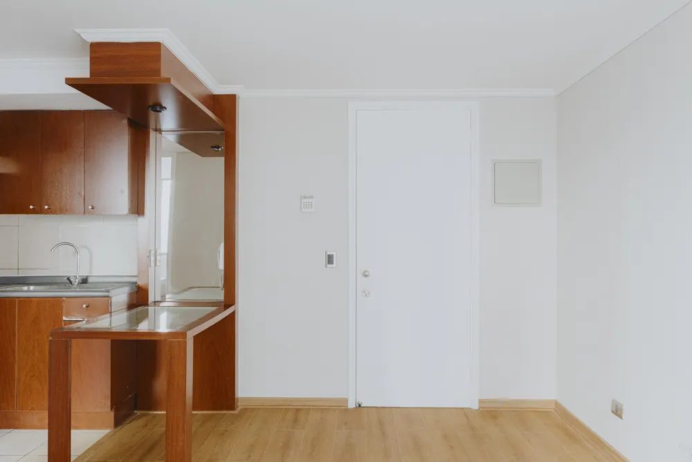 Living con cocina y puerta de acceso, departamento Av. Vicuña Mackenna 881